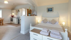 Un dormitorio con cama, mesitas de noche y vista a la cocina.