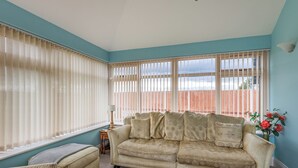 Una sala de estar con un sofá color beige, un reposapiés a juego y una lámpara.