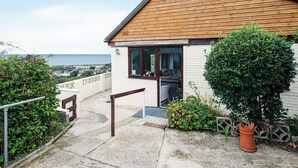 A small house with a wooden roof, a white brick exterior, and a view of the sea. - Frondeg translates to ’Pretty Hill’, this is exactly what this property offers. (Aberaeron)