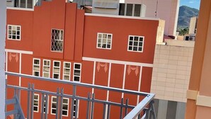 Un edificio rosso con molte finestre e una ringhiera metallica.