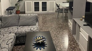 Un soggiorno con un divano, un tavolino, un mobile e un quadro appeso al muro.