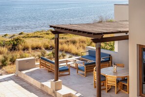 A patio with outdoor furniture, a pergola, and a view of the sea.