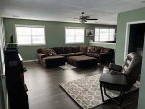 A living room with a sectional sofa, ottoman, and a leather chair.