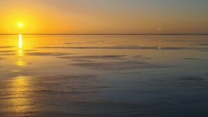 A beach at sunset with a calm sea and a clear sky. - 2 bedroom accommodation in Morecambe (Morecambe)