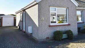 A single-story house with a white exterior, a front door, a small window, and a visible number plate. - 2 bedroom accommodation in Morecambe (Morecambe)