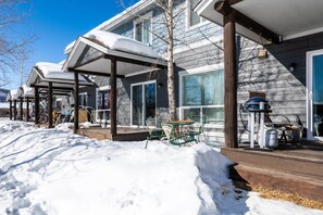 A residential property with a covered porch, outdoor seating, and a snow-covered landscape.