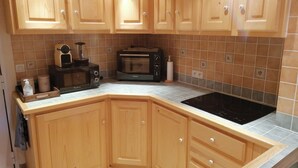 A kitchen with wooden cabinets, a microwave, a toaster, and a stovetop. - Duplex Apartment "The 529  (Bourg-Saint-Maurice)