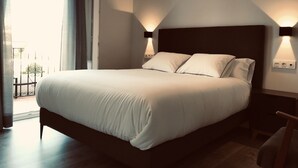 A neatly made bed with a dark headboard and two wall-mounted lights on either side. - Apartamentos Ciudad de Ronda (Ronda)