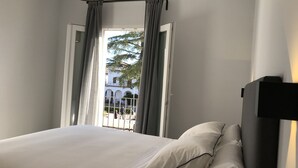 A bedroom with a bed, a window with curtains, and a view of a building outside. - Apartamentos Ciudad de Ronda (Ronda)