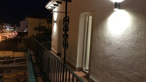 A balcony with a railing, a door, and a wall with a textured surface. - Apartamentos Ciudad de Ronda (Ronda)