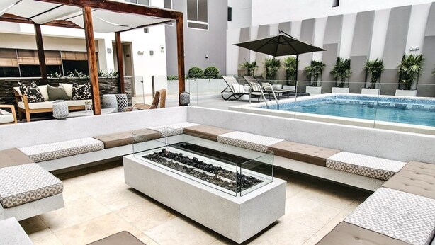 A modern outdoor seating area with a fire feature, pool, and lounge chairs. - Exclusive Apartments in Pedro Martinto by Wynwood-House (Lima)