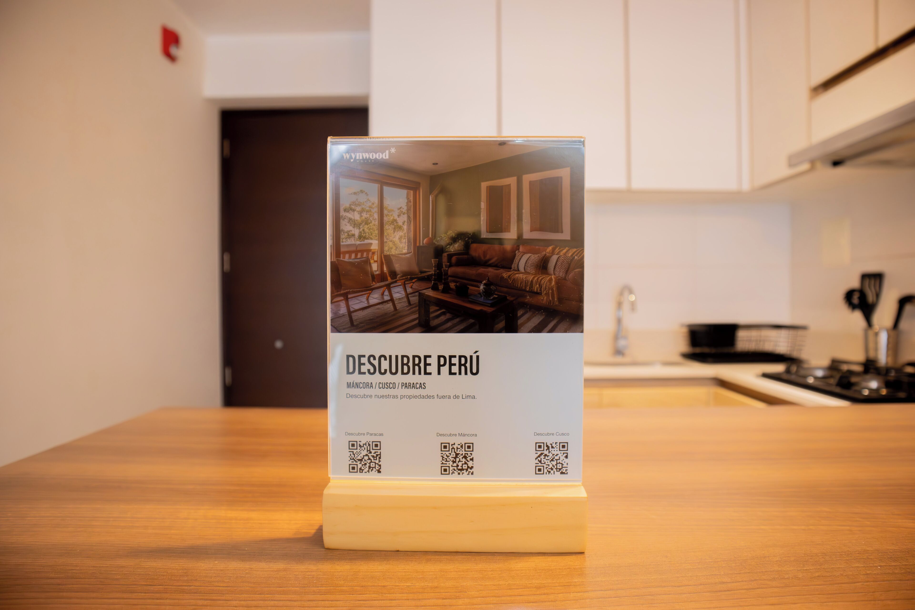 A QR code stand with a photo of a living room, a kitchen, and a door in the background.