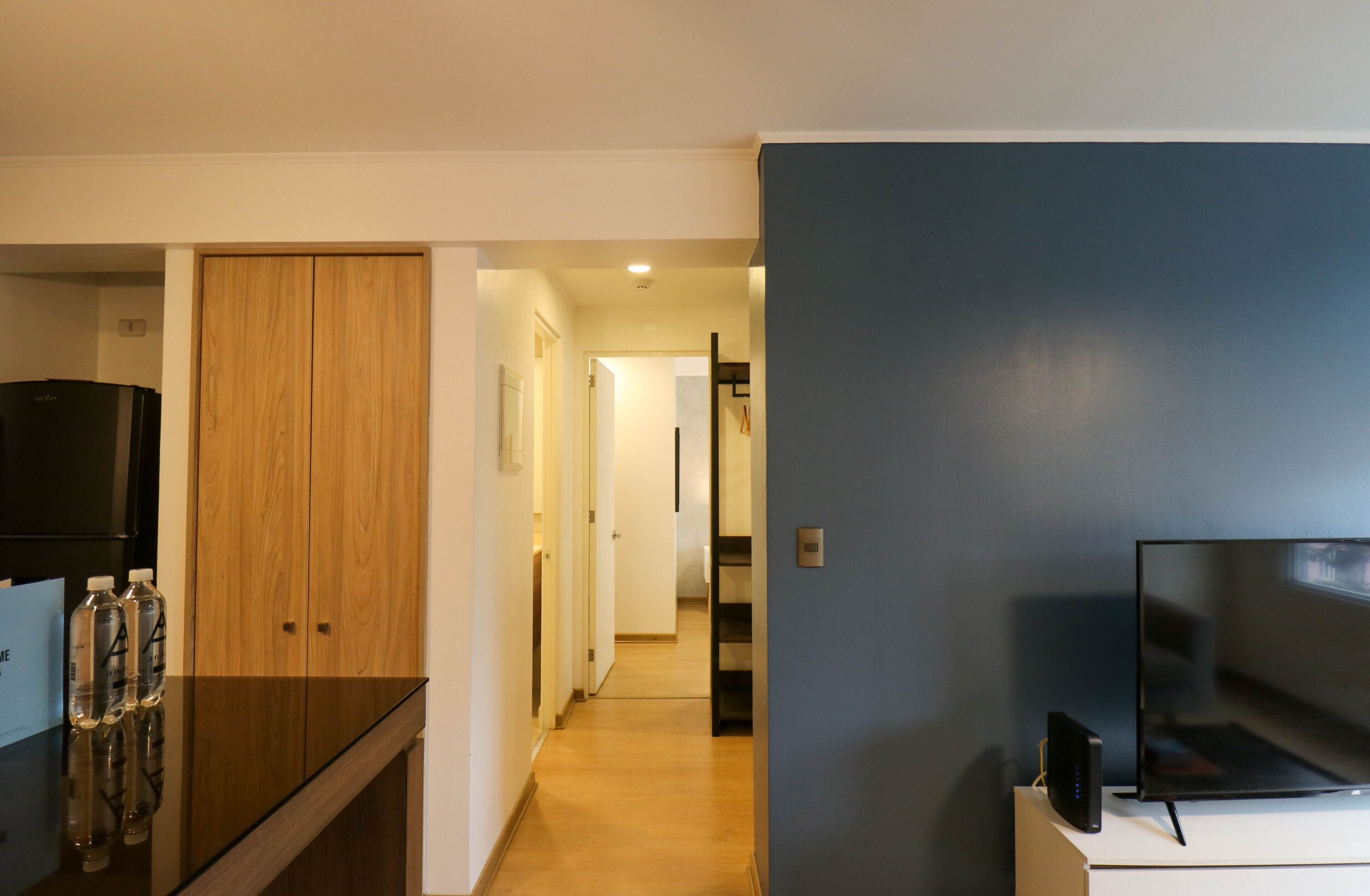 Une chambre d’hôtel moderne dotée d’une armoire en bois, d’un téléviseur à écran plat et d’un mini-bar.