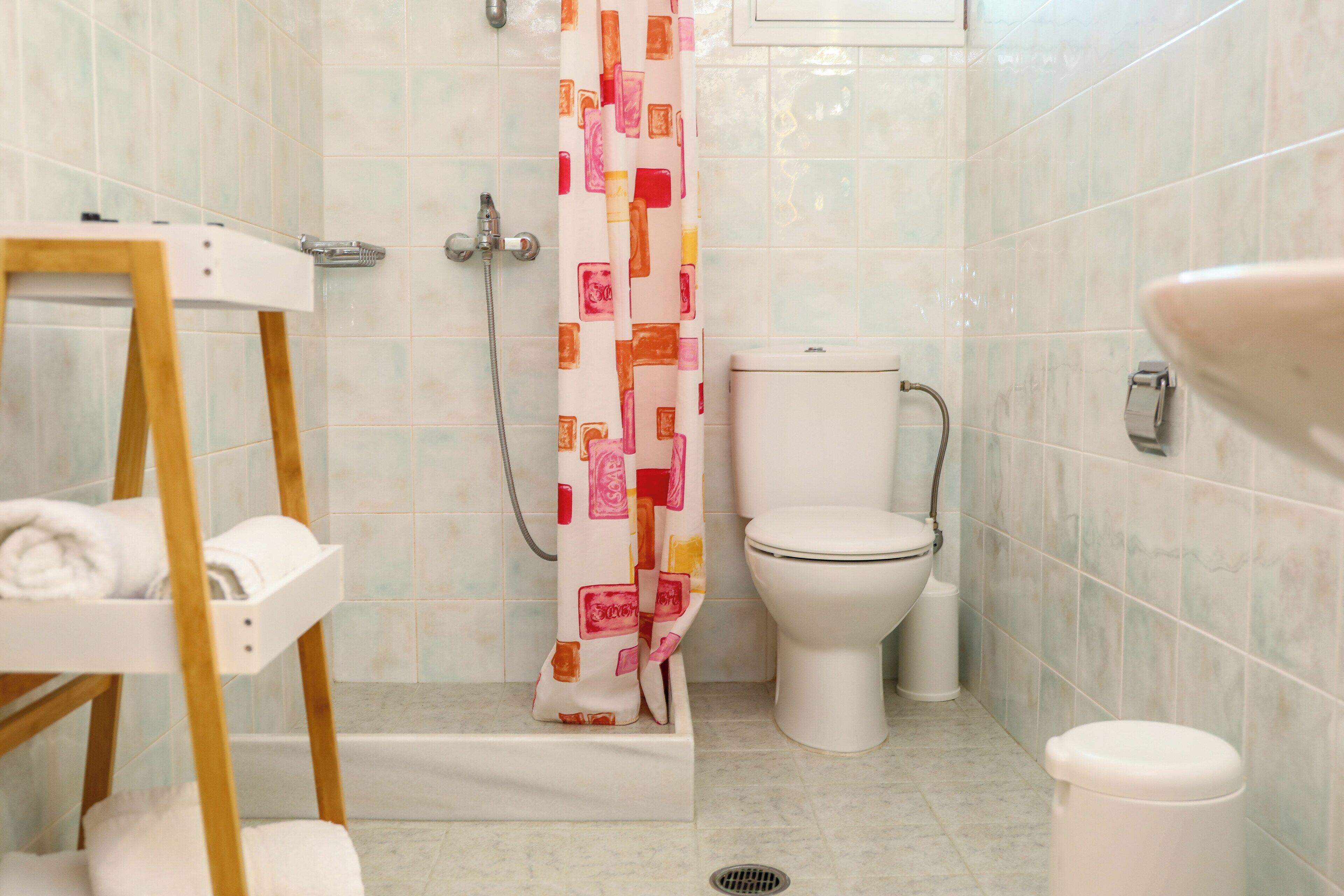 Ein Badezimmer mit Dusche, Toilette und einem Handtuchregal.