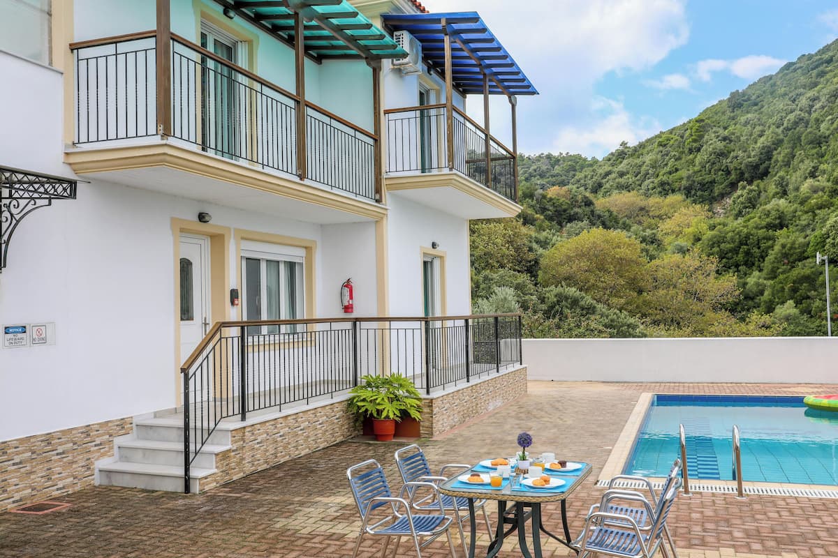 A two-story building with a balcony, a swimming pool, and outdoor seating.