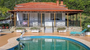 Una villa con piscina, una decoración de cisne y montañas al fondo.