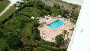 Vista aèria d'un complex turístic amb una piscina central, envoltada de gandules i palmeres.