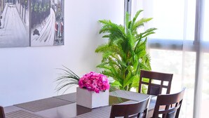 Uma sala de jantar com uma mesa, cadeiras, uma planta em vaso e obras de arte na parede.