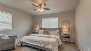 A bedroom with a bed, nightstands, a ceiling fan, and two windows with blinds. - 2-Bedroom Cottage w/ KING bed (Edmond)