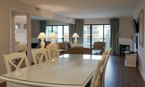 A modern living room with a dining table, chairs, sofas, and a fireplace.