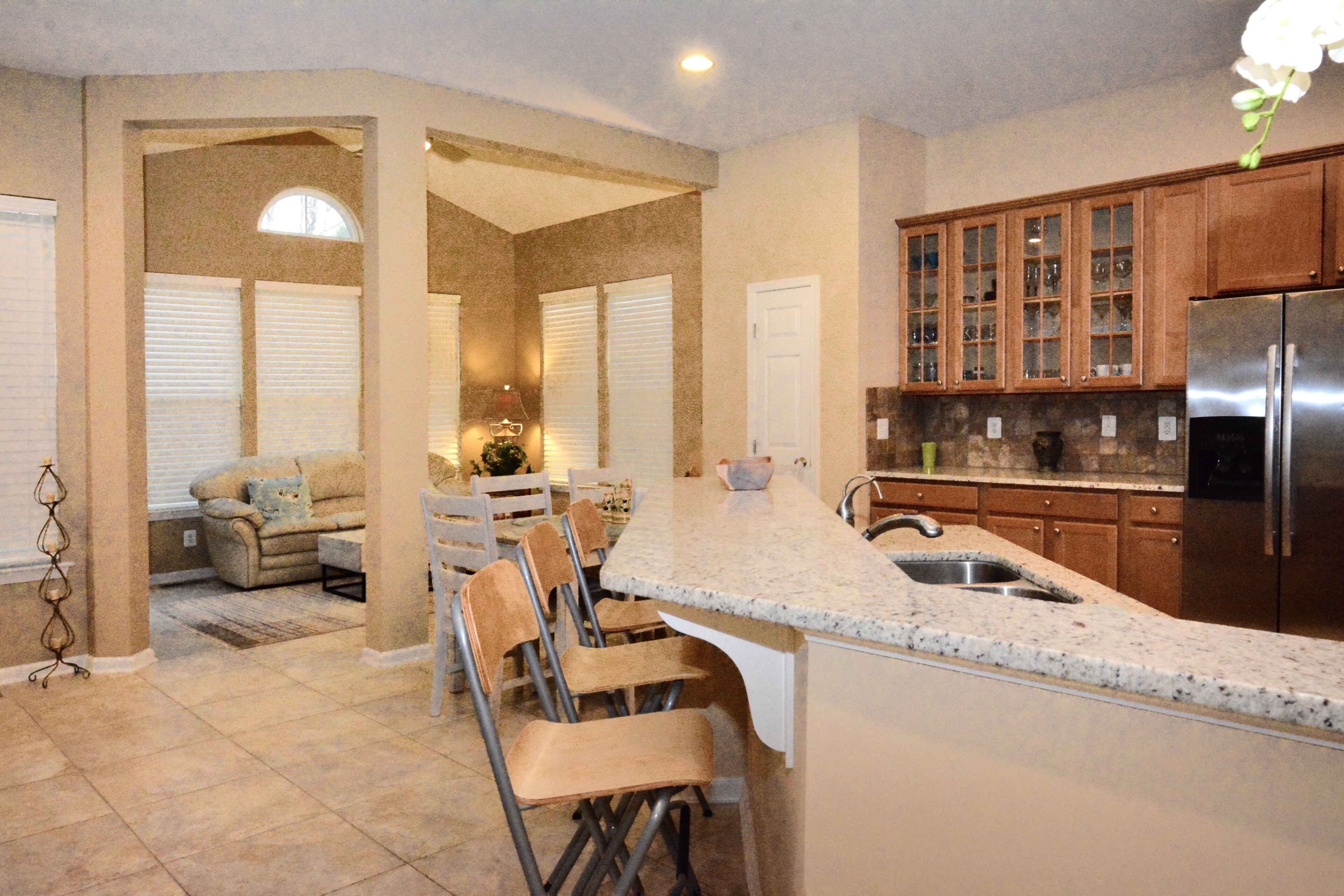 A kitchen with a granite countertop, stainless steel refrigerator, and wooden cabinets.