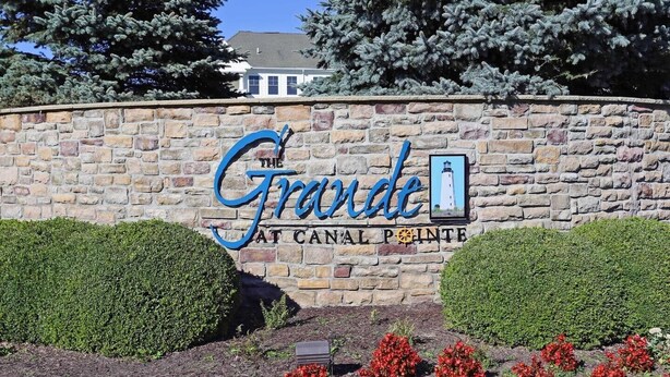 Un mur de pierre sur lequel est apposée une enseigne indiquant « The Grande Canal Pointe », avec une représentation graphique d’un phare.