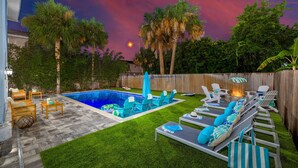 A backyard with a swimming pool, lounge chairs, and a fire pit. - Family Beach Escape with Heated Pool & Games (Jacksonville Beach)