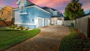 A residential house with a paved driveway, a garage, and a fenced backyard. - Family Beach Escape with Heated Pool & Games (Jacksonville Beach)
