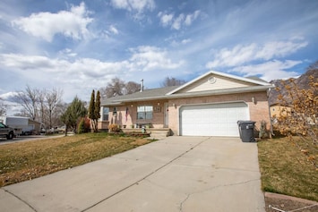 Your home's entrance boasts a welcoming driveway, leading to a secure garage for your vehicles. The front yard is a charming space with greenery, and well-placed trash cans maintain a tidy and organized outdoor environment.