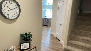 A hallway with a clock, a plant, and a framed certificate on a console table. - Gorgeous New Townhome with Hot Tub (Kanab)