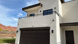 A modern two-story house with a garage, a balcony, and a number '15' on the facade. - Gorgeous New Townhome with Hot Tub (Kanab)