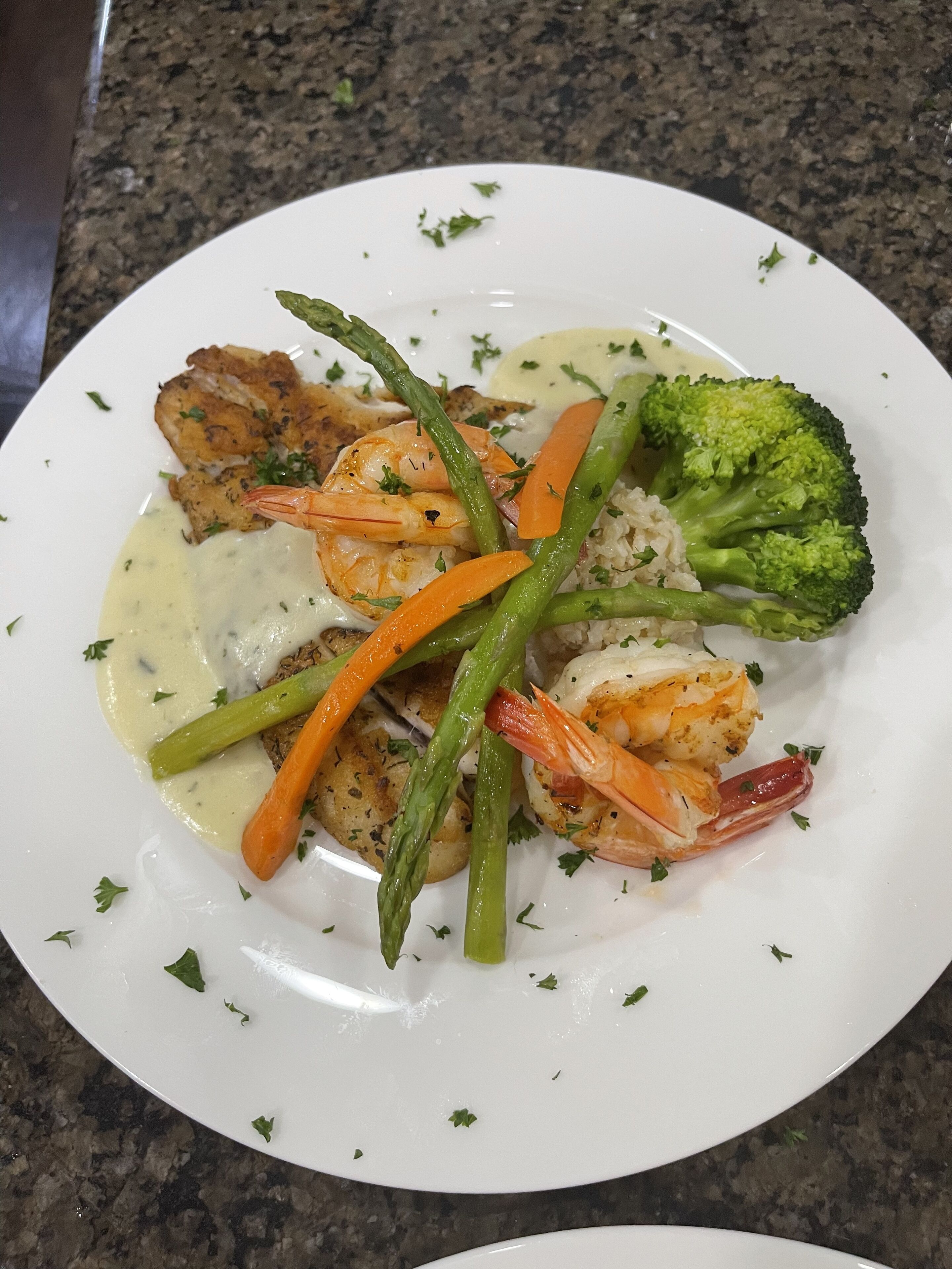 A plate of food with shrimp, asparagus, carrots, and broccoli.