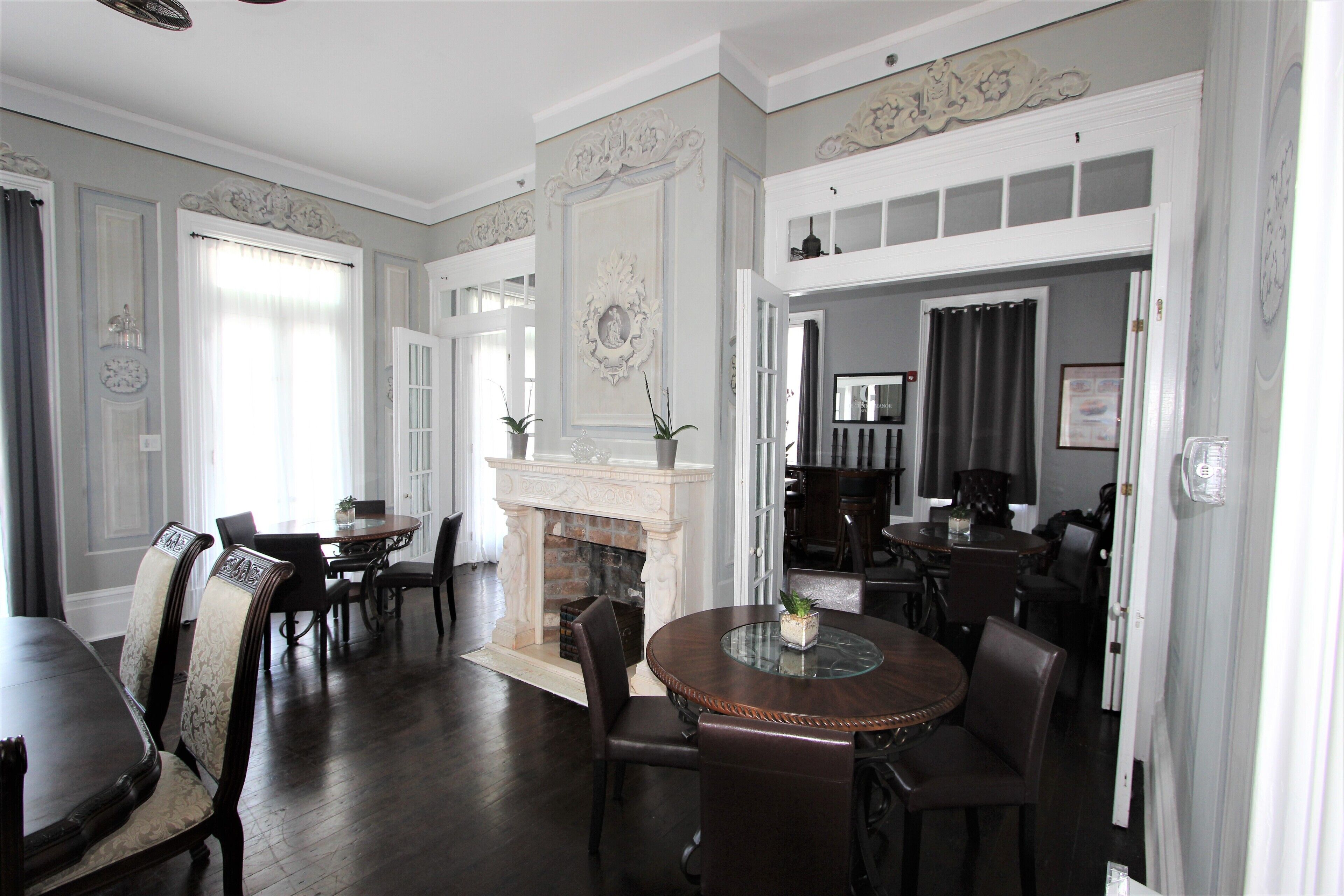A dining area with a round table, chairs, a fireplace, and a view into another room.