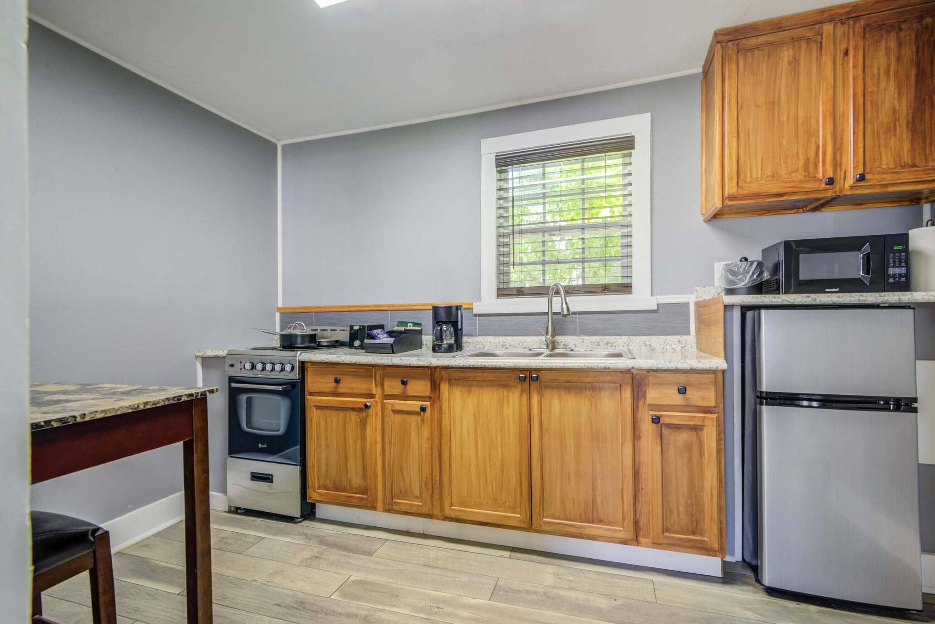 A kitchen with wooden cabinets, a built-in oven, a microwave, and a refrigerator.