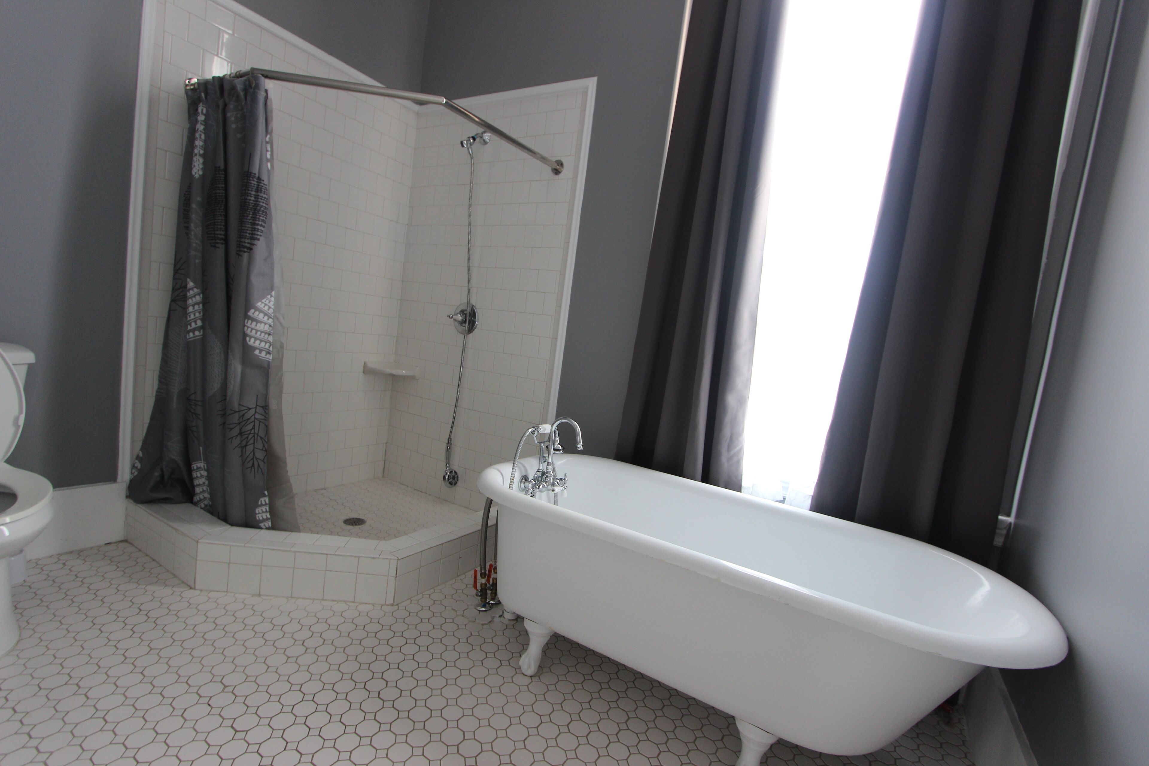 Een badkamer met een witte badkuip, douche en toilet.