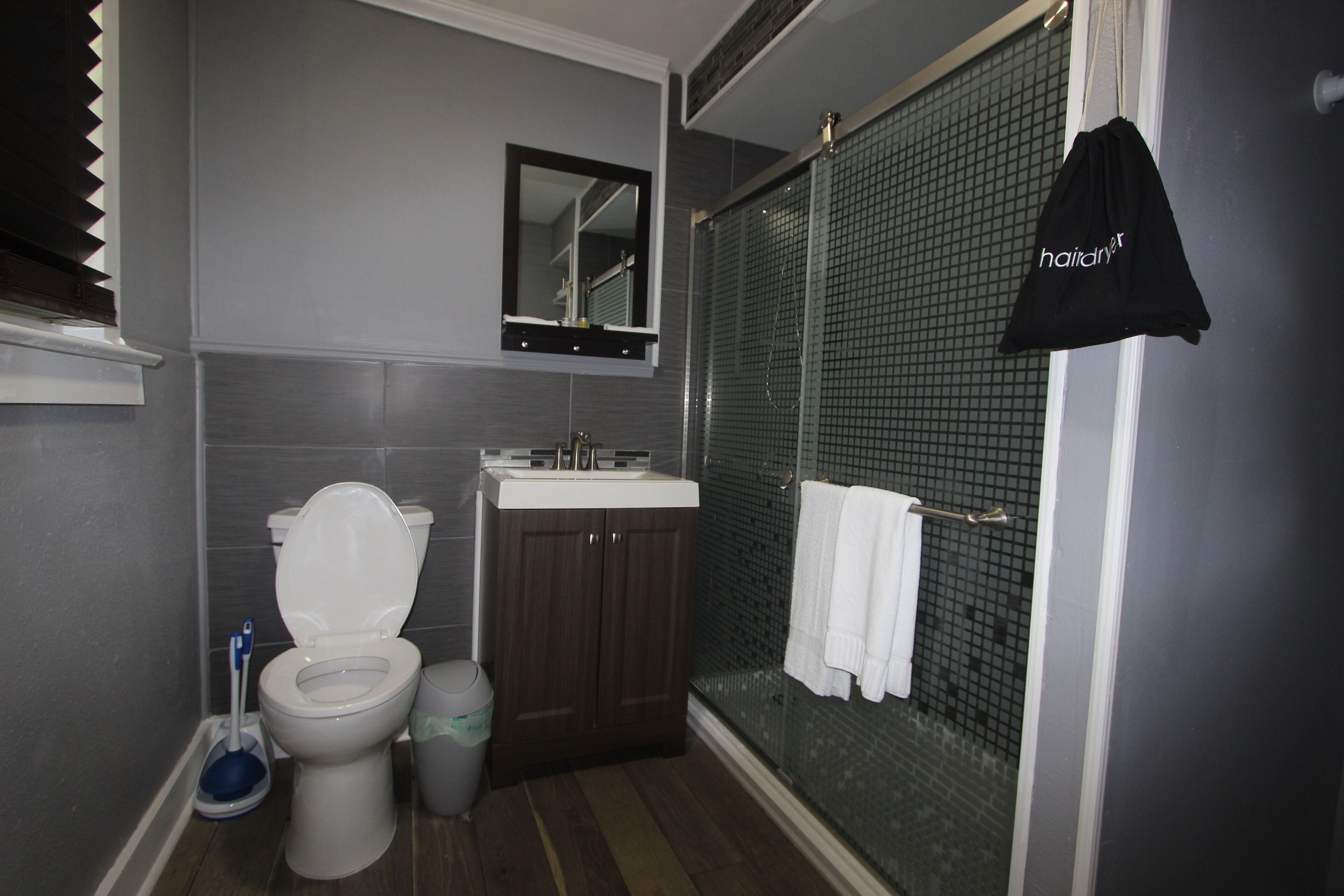 A bathroom with a toilet, sink, mirror, and a shower area.