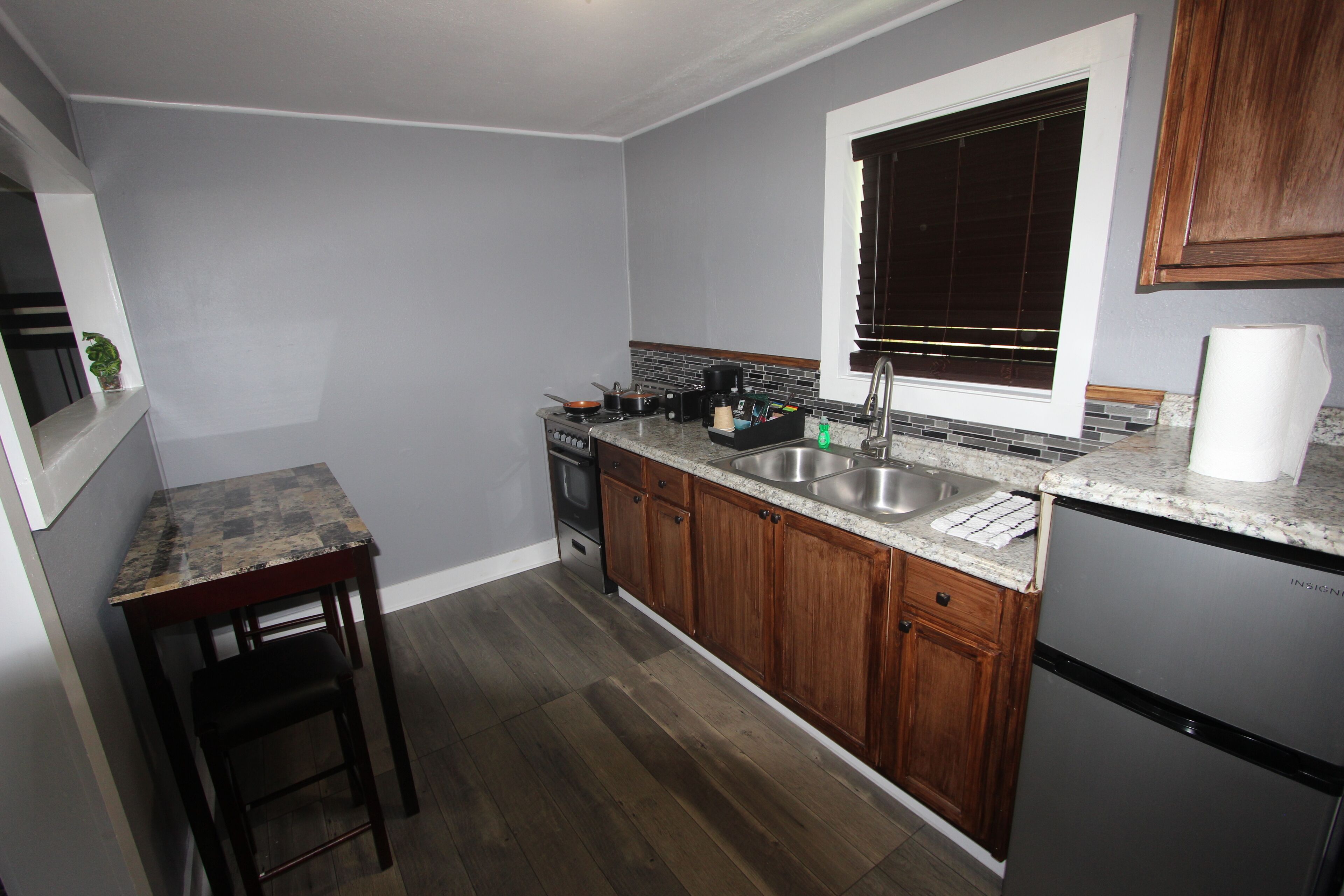 A kitchen with wooden cabinets, a granite countertop, a stainless steel sink, and a built-in oven.