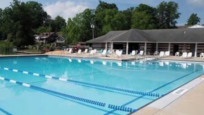 Une piscine avec des couloirs délimités, un plongeoir et des chaises longues.