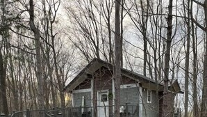 Un molo di legno conduce a una casa costruita su palafitte, immersa tra gli alberi.