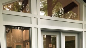Un portico coperto con un pontile in legno, una cassetta delle lettere rossa e una sedia in vimini.