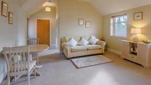 A cozy living room with a dining area, a sofa, a lamp, and a window with blinds. - The Parlour - UK36122 (Horsington)