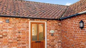 A brick building with a tiled roof, a wooden door, and a sign reading 'The Parlour.' - The Parlour - UK36122 (Horsington)
