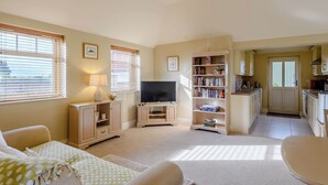 A living room with a TV, bookshelves, and a dining area. - The Parlour - UK36122 (Horsington)