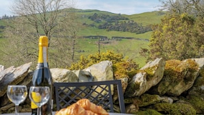 A table with a bottle of wine, two glasses, and a croissant. - 2 bedroom accommodation in Crook, near Windermere (Crook, near Windermere)