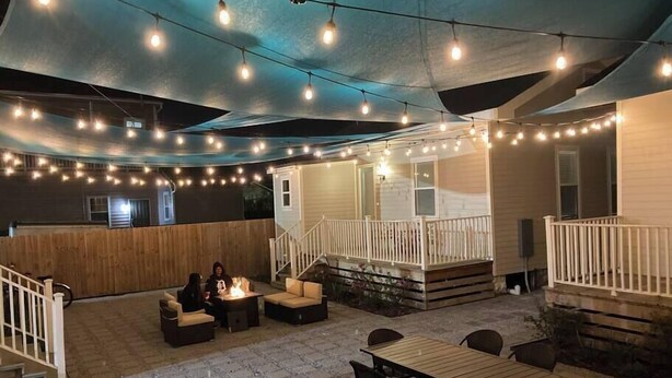 An outdoor patio area with string lights, a covered seating area, and a wooden deck. - Chic NOLA Villa: Pet-Friendly, Patio & Fire Pit (New Orleans)