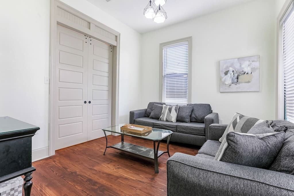 A living room with a sofa, a glass coffee table, and a door.