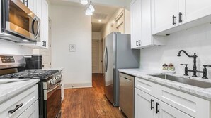 A kitchen with white cabinets, a stainless steel stove, a refrigerator, and a sink with a faucet. - Chic NOLA Villa: Pet-Friendly, Patio & Fire Pit (New Orleans)