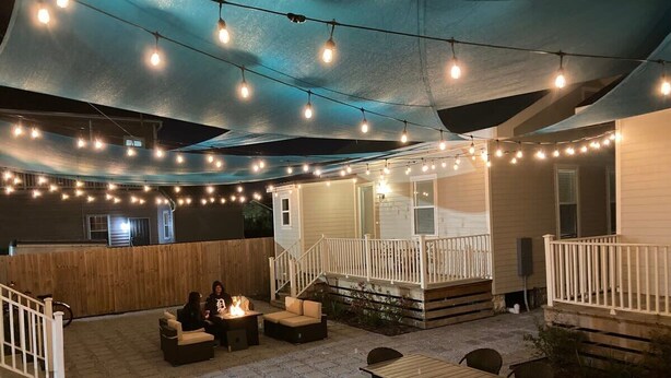 An outdoor patio area with string lights, a fire pit, and seating arrangements.