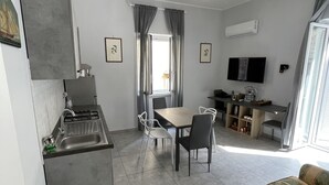 Un espace de vie compact comprenant une kitchenette, un coin repas et un coin salon.