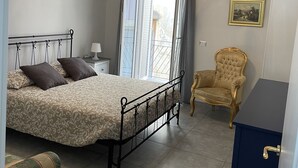 Une chambre à coucher avec un lit, une chaise, une armoire et une fenêtre avec des rideaux.